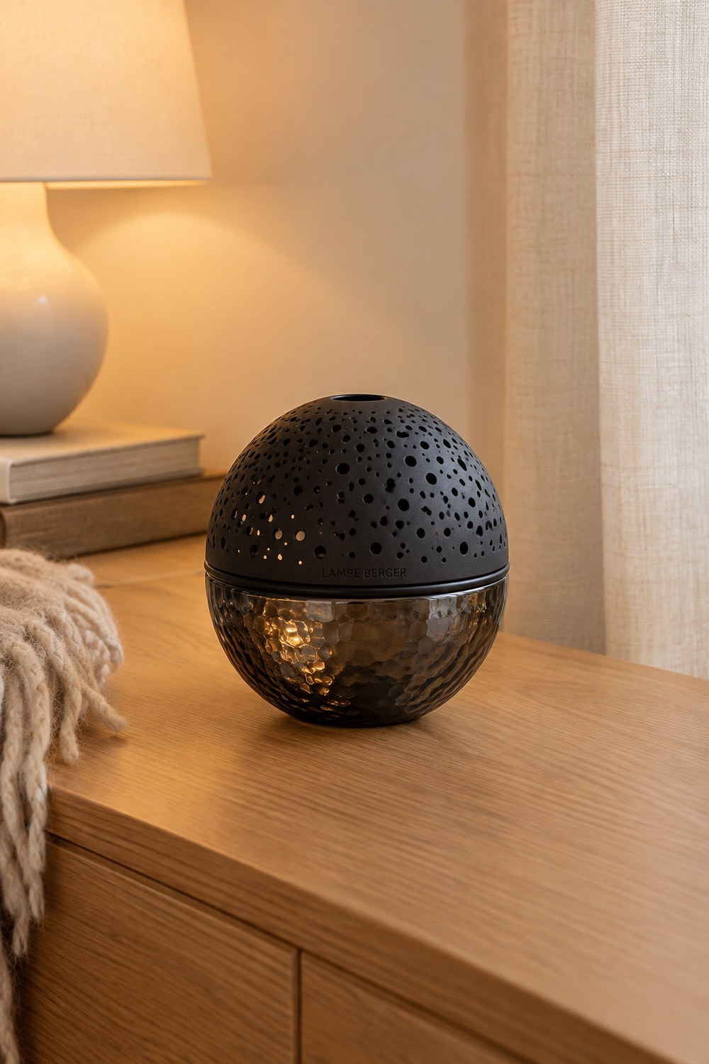 Lampe Berger Gravity in Schwarz mit gelochter Kuppel und gehämmertem Rauchglas im gemütlichen Wohnzimmer am Abend