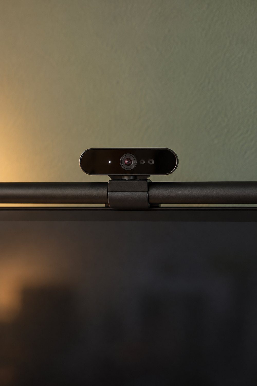 Logitech BRIO 4K Webcam auf einer schwarzen Monitor-Lichtleiste vor einer salbeigrünen Wand